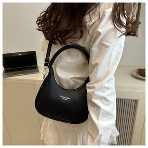 Minimalist black leather hobo bag with white text logo styled in a warm home setting