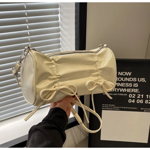 Detail of cream pillow bag with pleated texture and stylish double bow decorations