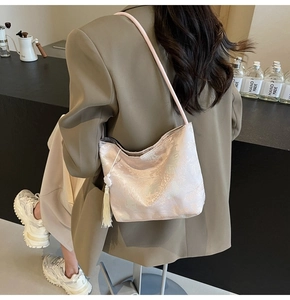 Close-up of pink textured shoulder bag with white tassels on elegant model