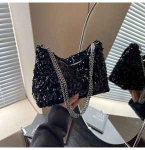 Detail of a chic black sequined handbag with shimmering surface and silver chain strap