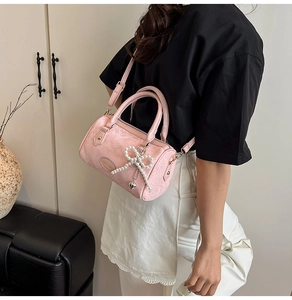 Close-up of pink pillow bag with pearl bow, heart charm and embossed texture details