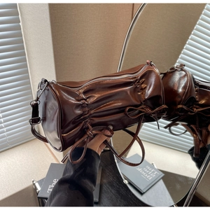 Detailed view of the dark brown pillow bag with pleated texture and bow ribbon accents