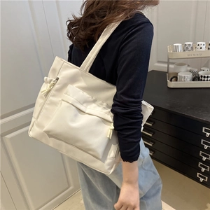 Borsa tote beige minimalista di grande capacità con tasca frontale indossata da una modella