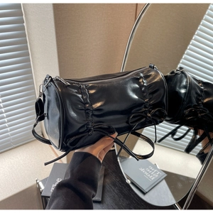 Detail view of black glossy leather pillow bag with stylish ruffles and bow accents
