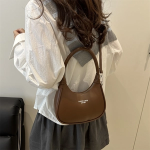 Brown leather half-moon hobo bag shown from side-back view on a model as a crossbody bag