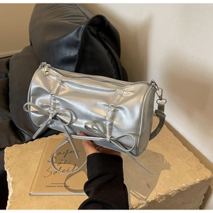 Detailed view of silver metallic pillow bag with bow accents and pleated texture