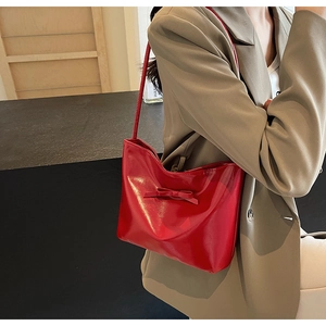 Detail of red patent leather shoulder bag with a stylish matching bow decoration