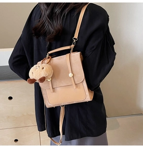 Detail of vintage khaki patchwork shoulder bag with plush pendant and matte finish