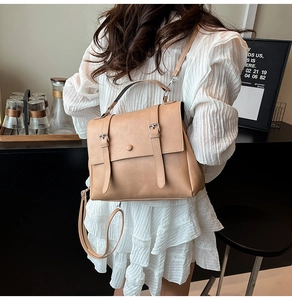 Khaki retro crossbody bag with double buckle straps shown in a cozy cafe setting