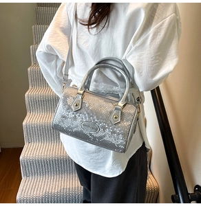 Detailed view of silver snake-pattern pillow bag with golden hardware and fashion tag