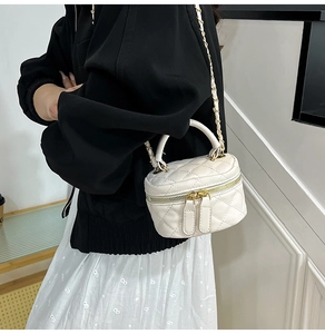 Detail of white quilted leather mini cylinder bag with gold chain and dual zipper