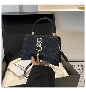 Dettaglio borsa a mano nera glitterata con logo SS argento e nappina metallica