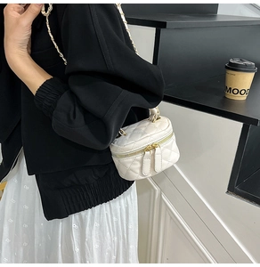 Detail of white quilted mini vanity bag with gold chain strap and top handle on model