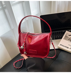 Detail of red glossy leather bag featuring chain strap and Fashion label on the side