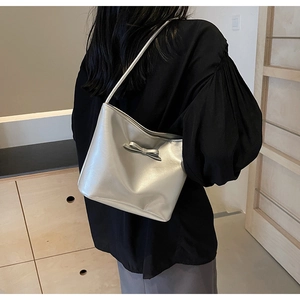 Detail of silver metallic underarm bag with decorative leather bow and slim shoulder strap