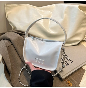 Close-up of white leather handbag with Fashion label and elegant metal chain strap