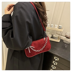 Détail du sac à bandoulière en daim bordeaux avec chaîne argentée et nœud strass