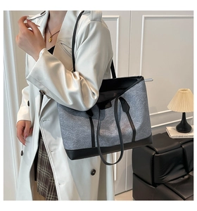 Model wearing a large grey felt tote bag with black leather trim and top handles