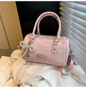 Detail of pink snake-embossed pillow bag with pearl bow charm and logo plaque