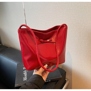Detail of red glossy patent leather tote bag featuring a minimalist bow decoration
