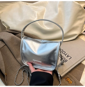 Détail d'un sac à main argenté métallisé avec texture ondulée et logo Fashion en métal