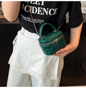 Detail of dark green quilted leather mini bag with gold chain strap and handle