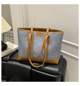 Detail of grey felt tote bag with tan leather trim and minimalist fashion text label