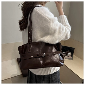 Detail of dark brown glossy tote bag with vintage belt buckle in a daily life scene