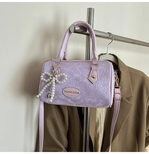 Détail du sac Boston violet clair avec texture reptile et pendentif nœud en perles