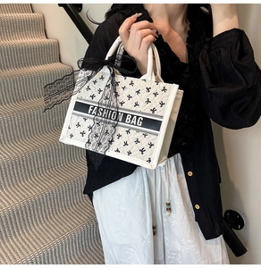 Detail of white tote bag featuring black bow patterns and elegant lace ribbon decoration