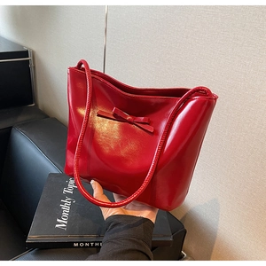 Detail of red patent leather tote bag with glossy finish and delicate bow decoration