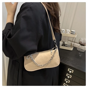 Vue latérale du sac sous le bras en daim beige avec chaîne argentée sur un mannequin