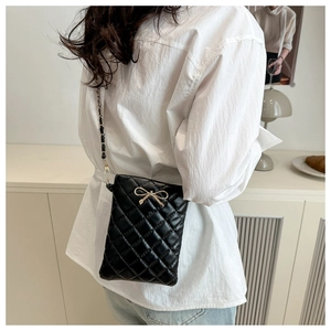 Détail du sac bandoulière matelassé noir avec boucle dorée et bandoulière sur modèle
