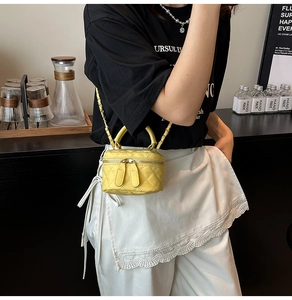 Detail of yellow quilted leather mini vanity bag with gold chain strap and top handle