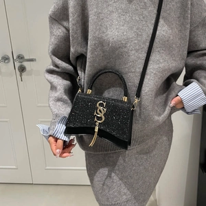 Borsa a tracolla nera glitterata con logo oro e nappa su completo in maglia grigia
