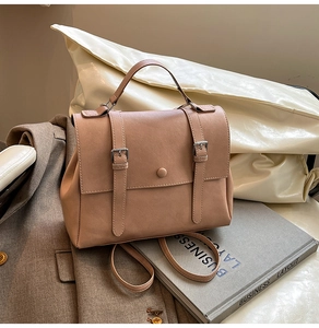 Detailed macro view of milk tea matte leather texture and retro buckle straps on bag