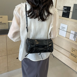 Minimalist black leather pillow bag with stylish bow details and pleats shown on model