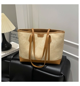Close-up of canvas tote bag with contrast leather trim and embossed fashion patch