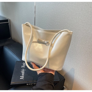 Close-up of a cream white shoulder bag with a decorative bow and smooth PU leather finish