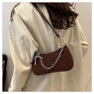 Brown suede baguette bag with silver chain and pearl star pendant on shoulder