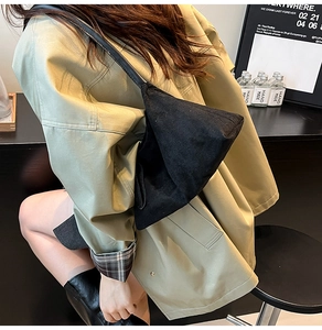 Detail of minimalist black triangular canvas shoulder bag with soft textured fabric
