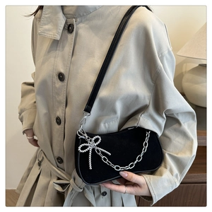 Détail du sac noir mat avec un nœud en perles argentées et une chaîne métallique