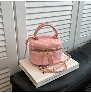 Detail of pink quilted leather mini bucket bag with gold chain strap on white books
