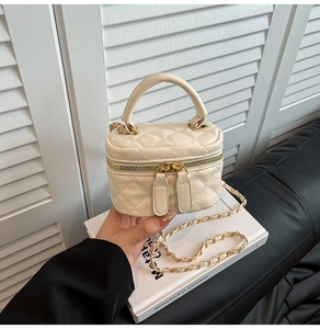 Detail of mini quilted beige vanity bag featuring gold chain strap and dual zippers