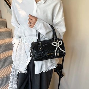 Fashionable black snake pattern cylinder pillow bag with pearl bow and heart charm on a model