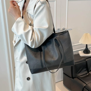 Minimalist large capacity tote bag in dark grey with black leather straps on a model