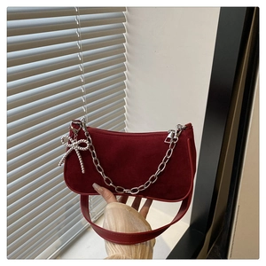 Détail du sac baguette en daim bordeaux avec chaîne argentée et charm noeud élégant