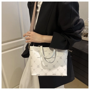 Minimalist white bucket bag with animal print and wide strap shown on model's shoulder