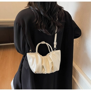 Close-up of off-white pleated cloud bag with shiny texture and adjustable strap
