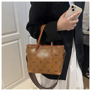 Detail of brown litchi texture bucket bag with bear monogram print and woven strap